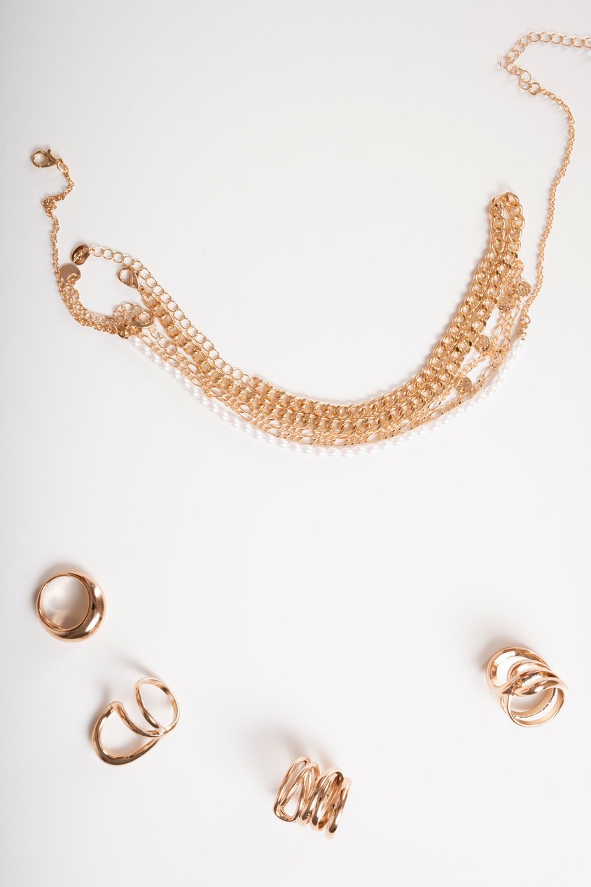 Photo of necklaces and rings top view on white background